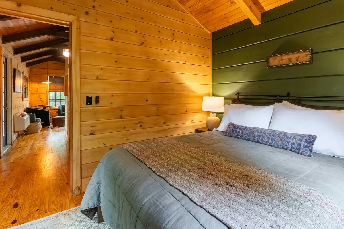 Queen bedroom with view into the living area inside The Roost cabin in Lake Lure, North Carolina
